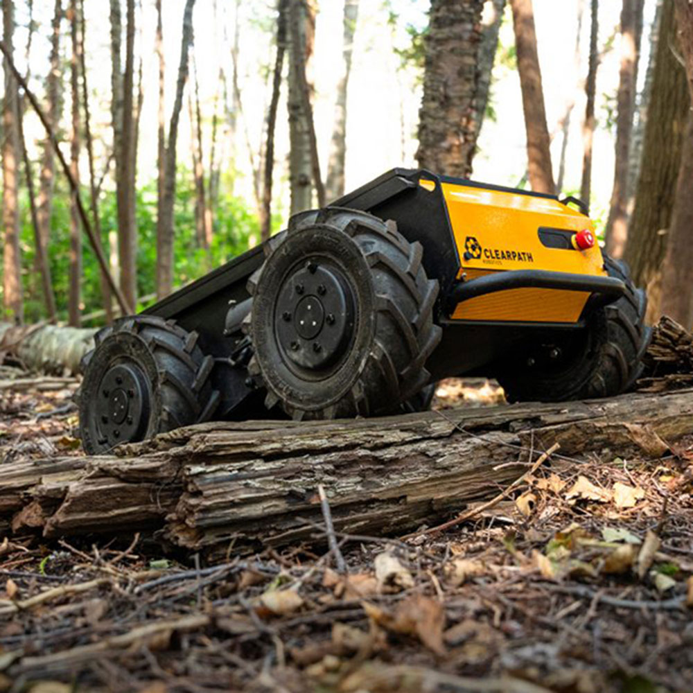 Husky robot moving over ground debris in forest